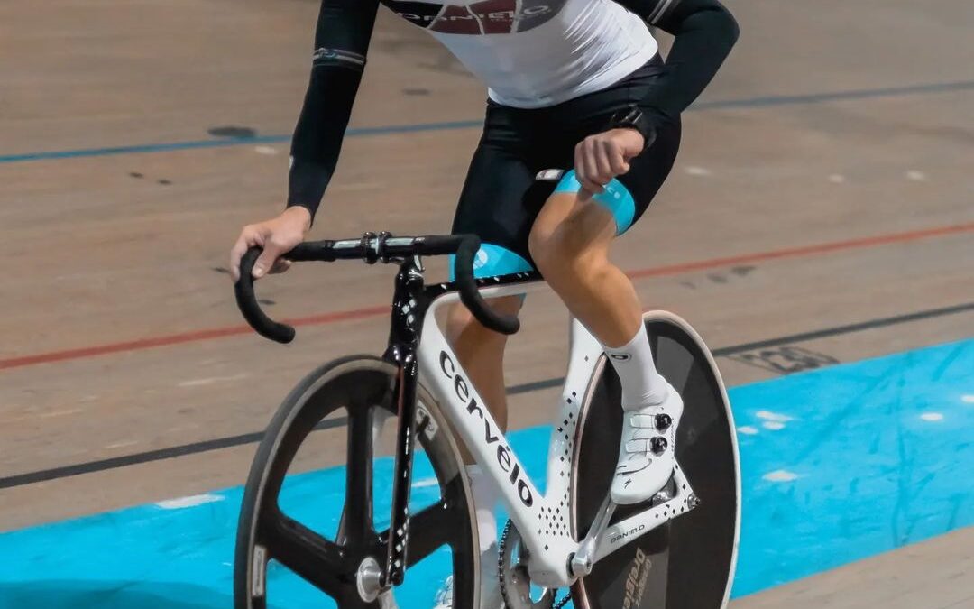 Professional cyclist racing on an indoor velodrome track using a time trial bike