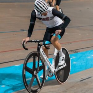Professional cyclist racing on an indoor velodrome track using a time trial bike