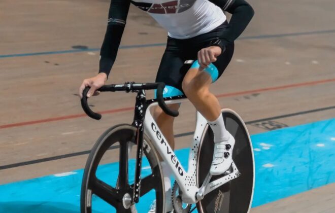 Professional cyclist racing on an indoor velodrome track using a time trial bike